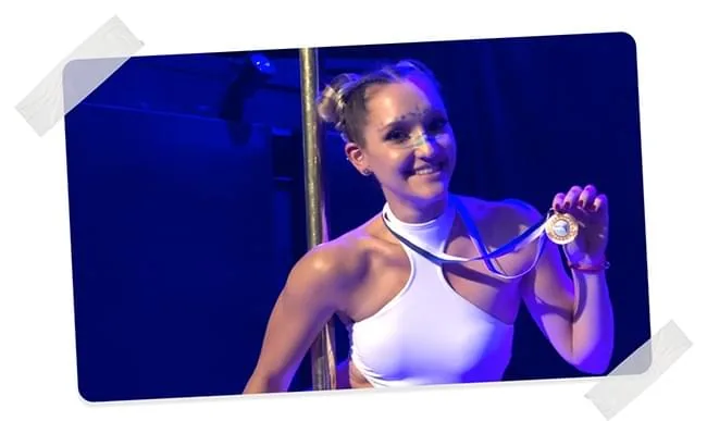 Hanna Pliasetski smiling while holding a gold medal after a successful performance.
